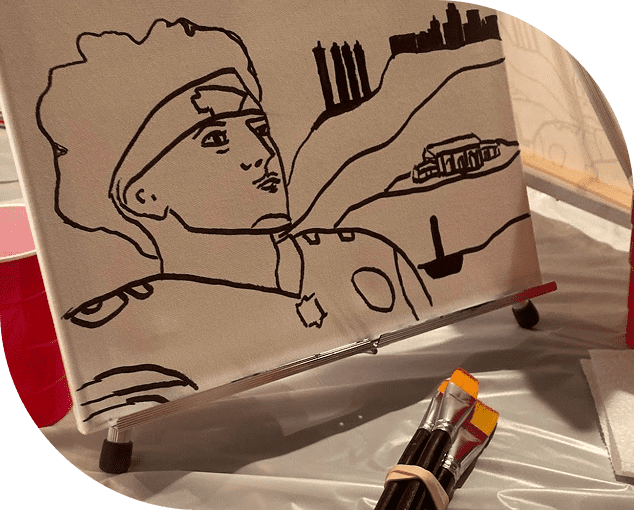 Black outline drawing of a football player on a canvas, situated on an easel with paintbrushes and a red cup nearby.